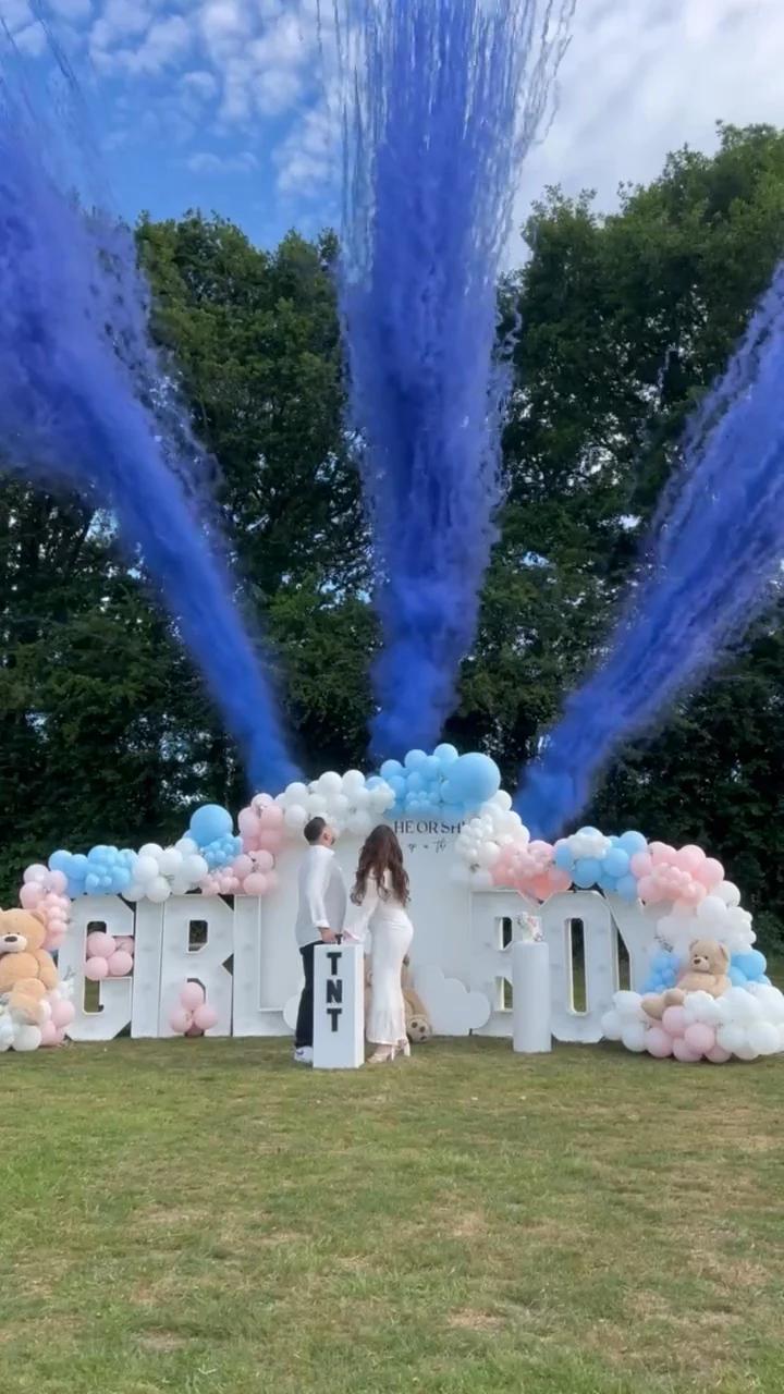 Three blue smoke plumes rise above a balloon display and white reveal letters. Illustrative reveal footage; effects vary by package.