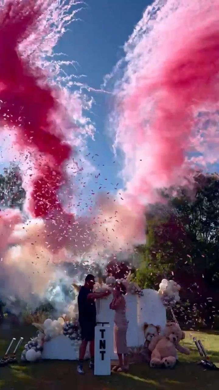 Pink smoke and confetti fill the sky above a sunny garden celebration. Illustrative reveal footage; effects vary by package.